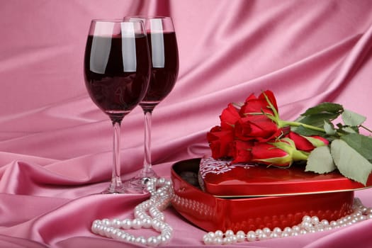 Heart-shaped red box with sweets, two glasses of red wine  and bunch of flowers. Valentine&#039 s day card.