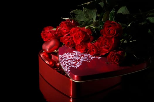 Heart-shaped red box and flowers on a black background. Valentine&#039 s day card.