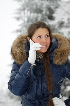The beautiful girl with a mobile phone in winter park.