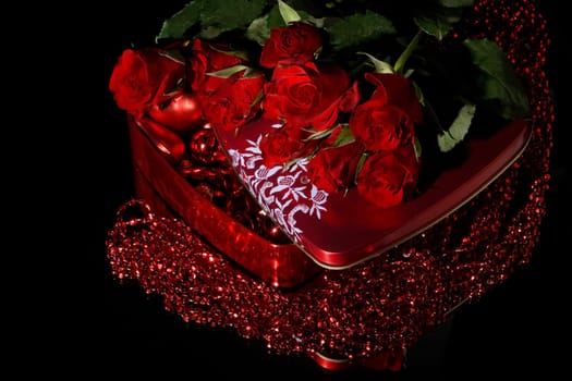 Heart-shaped red box and flowers on a black background. Valentine&#039 s day card.