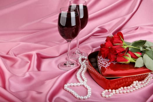 Heart-shaped red box with sweets, two glasses of red wine  and bunch of flowers. Valentine&#039 s day card.