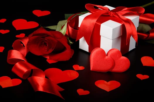 Gift box, red hearts and rose on a black background. Valentine&#039 s day card.