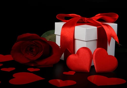 Gift box, red hearts and rose on a black background. Valentine&#039 s day card.