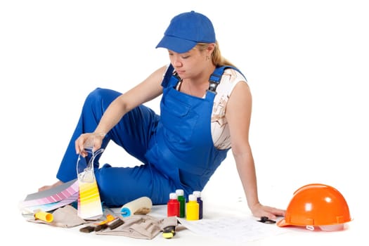 The pregnant woman dressed in working overalls, chooses colour for a children&#039 s room.