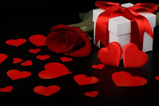 Gift box, red hearts and rose on a black background. Valentine&#039 s day card.