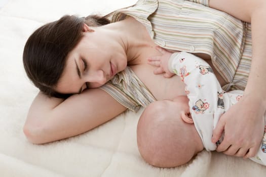 Young mum nurses the child on a white background