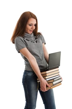 The attractive student stands with the laptop and books on a white background.