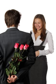 The young enamoured man with flowers and his girlfriend on a white background. Selective focus on flowers.