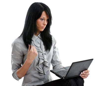 The attractive student sits on a pile of books with the laptop on a white background.