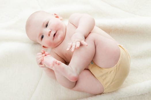 Sweet small baby lies on a white blanket.