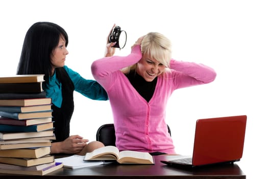 Two girlfriends of the student prepare for examination, sitting at a table on a white background.