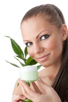The attractive girl with a branch of a bamboo and a cosmetics jar on a white background