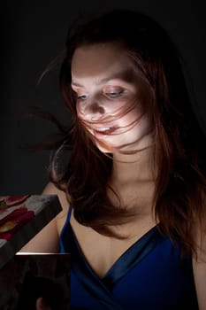 The girl opens a gift on a black background.