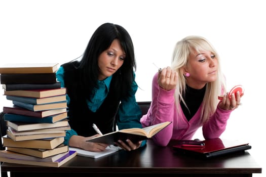 Two girlfriends of the student prepare for examination, sitting at a table on a white background.