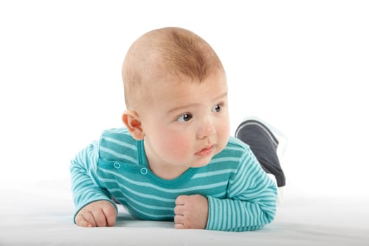 The nice small child in striped rompers lays on a stomach on a white background.