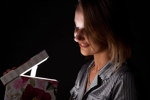 The girl opens a gift on a black background.