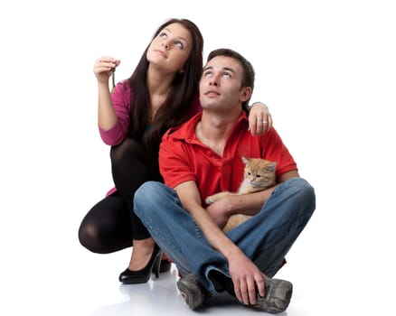 The young happy family with kitten and house keys in hands on a white background. House purchase concept.