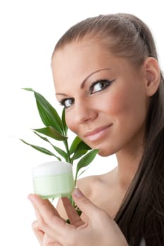 The attractive girl with a branch of a bamboo and a cosmetics jar on a white background