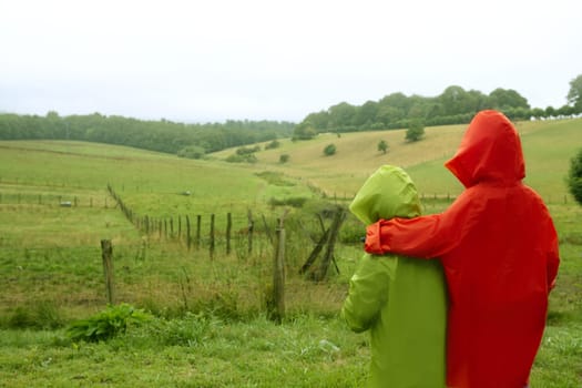 Green meadow with plastic waterproof coat colorful family in front