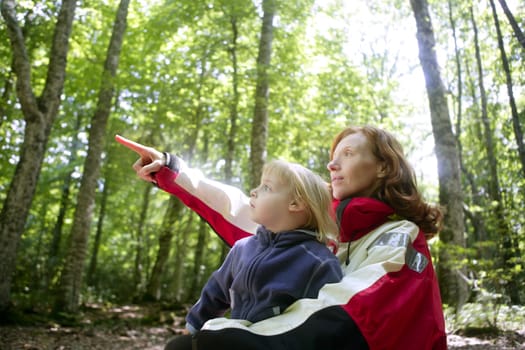 Beautiful blond little daughter with her mother inn the forest