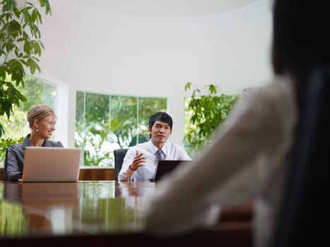 Young business people with laptop computers at meeting in conference room. Front view, copy space
