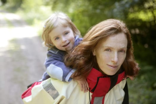 Beautiful blond little daughter with her mother inn the forest