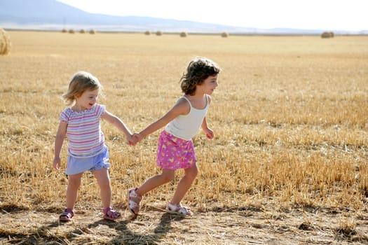 Girls playing with the round wheat dried bales outdoor summer