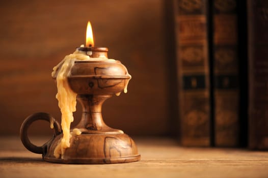 old candle on a wooden table, old books in the background