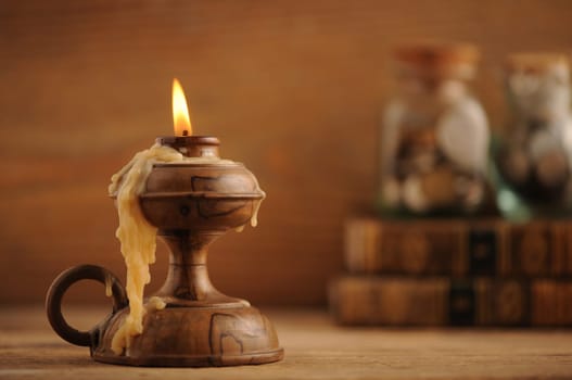 old candle on a wooden table, old books in the background