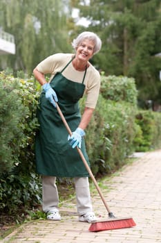 Active senior woman with a broom