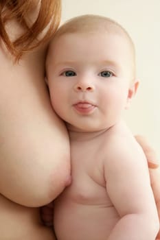 mother holding nude baby in arms on her breast