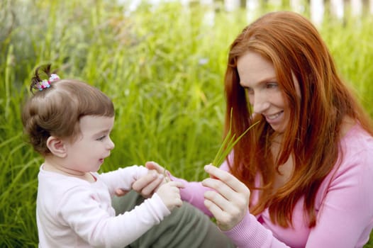 baby and redhead mother outdoor grass playing park together