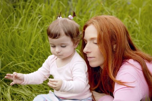 baby and redhead mother outdoor grass playing park together