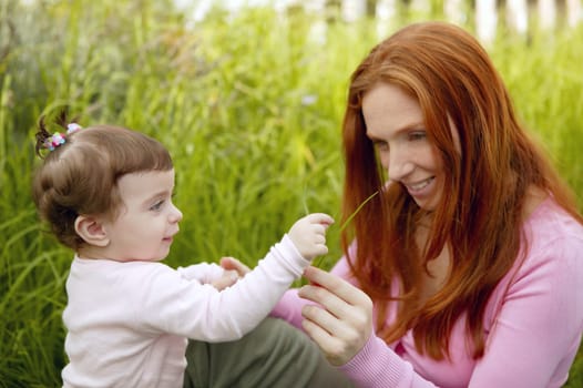 baby and redhead mother outdoor grass playing park together
