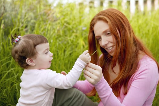 baby and redhead mother outdoor grass playing park together