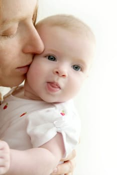 mother kissing little baby smiling on white background