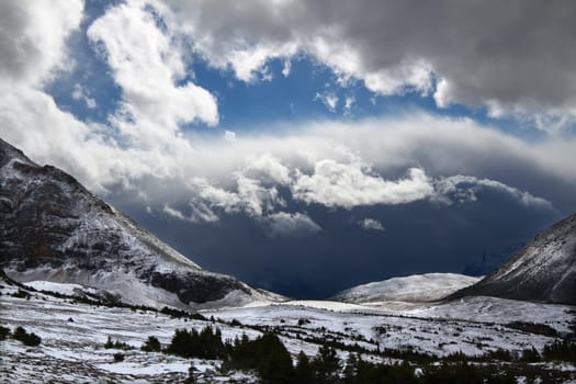 Sunlight shines through dark storm clouds near Mount Edith Cavell of Jasper National Park in Canada.