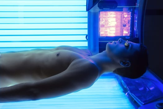 Tanning solarium young man lying real light on