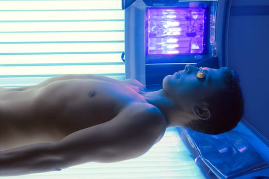 Tanning solarium young man lying real light on