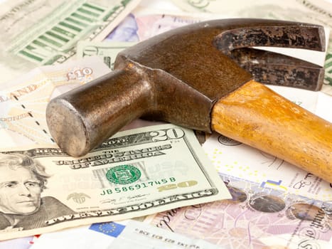 Macro of old hammer on top of dollar note to illustrate currency crisis in Europe