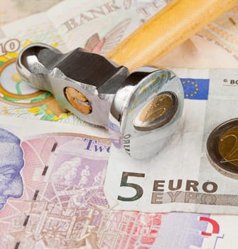 Macro of shiny hammer on top of euro note to illustrate currency crisis in Europe