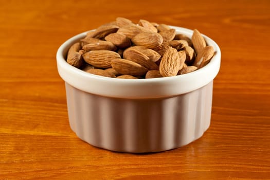 Pile of almond nuts in a porcelain bowl ready as a snack