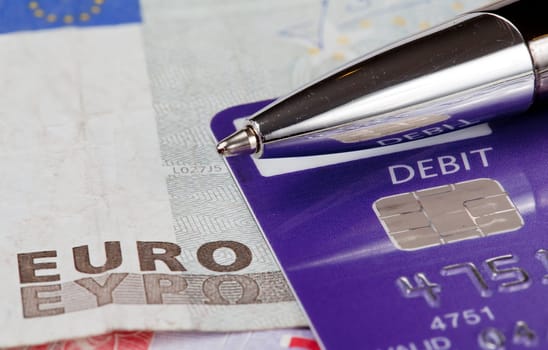 Macro of debit card and pen on top of euro note to illustrate currency crisis in Europe