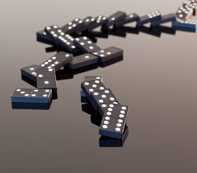 Macro image of dominos on a black reflactive surface and collapsed in pile