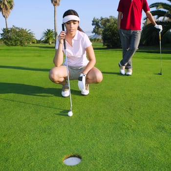 playing golf young woman looking and aiming for the hole