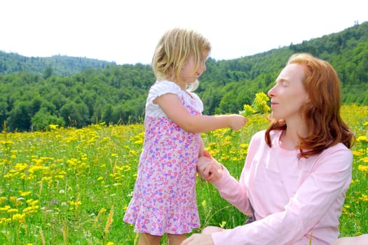 Daughter and mother playing in spring flowers meadow outdoor