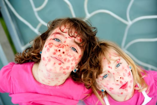 child sister girls mischief with mother lipstick painted face pretending measles