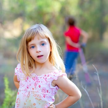 blond kid girl in forest park posing to camera