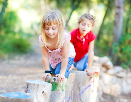 kid girls playing on trunks knee walking in forest nature