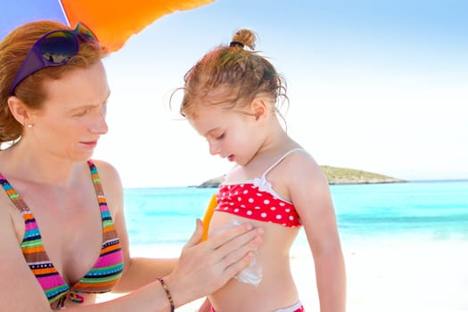 daughter and mother in beach with sunscreen in bikini